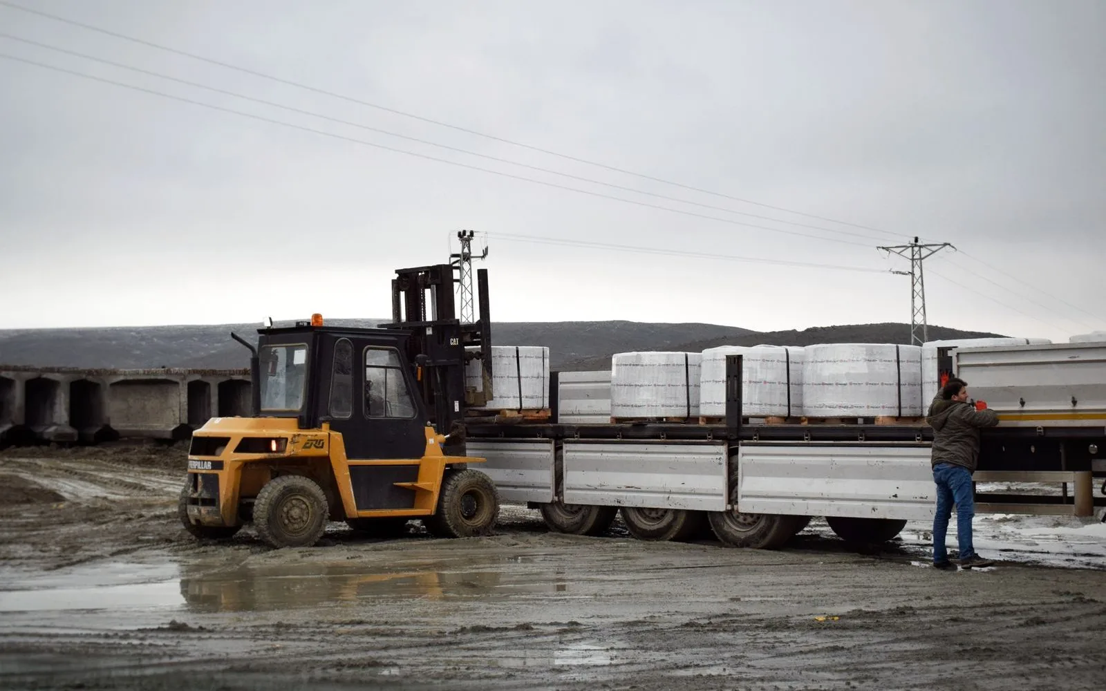 Lorry transport service Singapore: palletised load being lifted onto a flatbed lorry at ground level